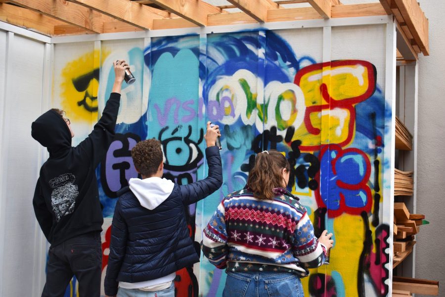 From left to right, Theo Fleig, Sebastian Johnson, and Nina Smith practice graffiti in the wood shop.