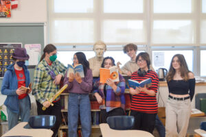A group of Latin club students showing off books and a bust of Julius Ceasar.