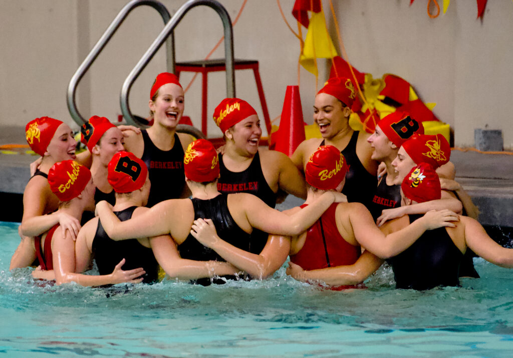 Girls water polo forms a huddle.