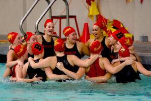 Girls water polo forms a huddle.