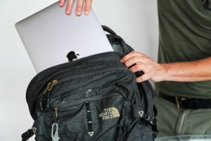 A student puts a laptop into their backpack.